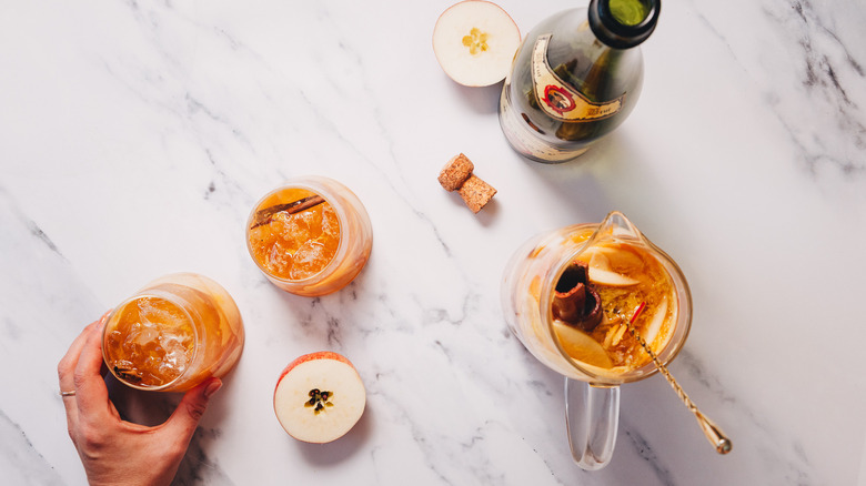 Hand holding one of two glasses of apple sangria
