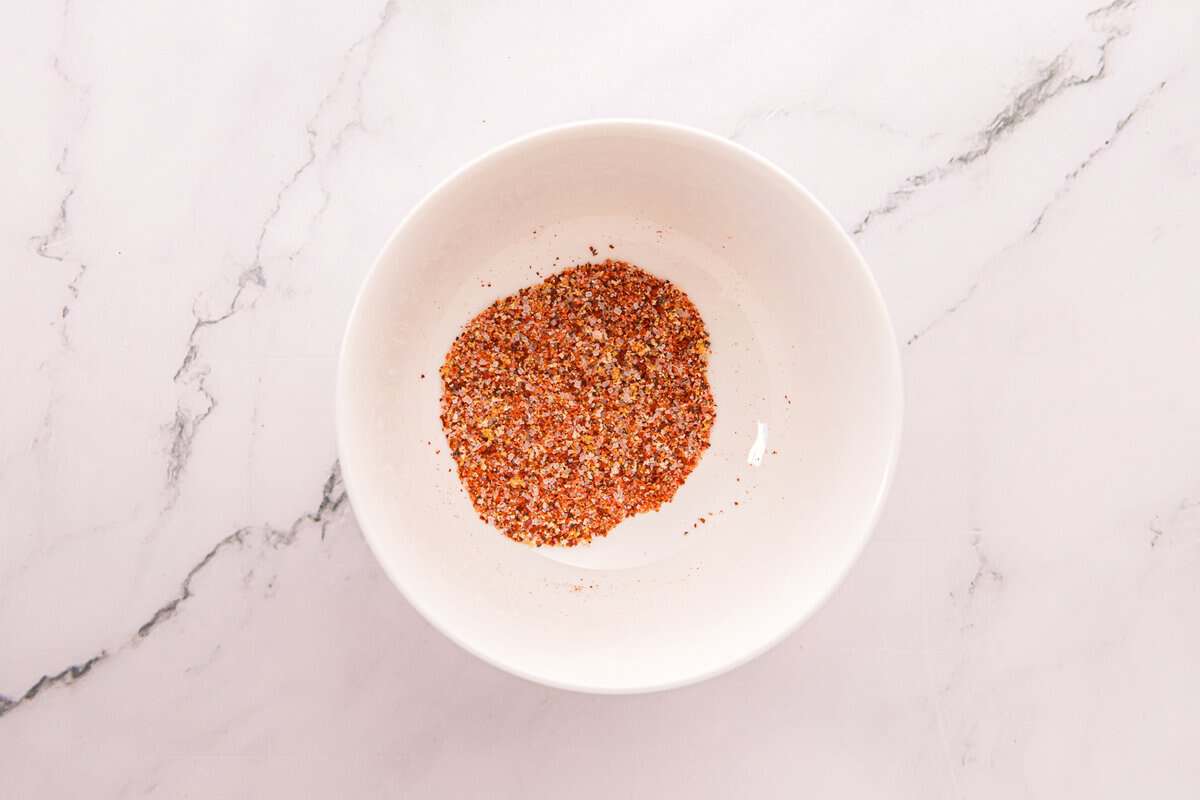 Overhead view of the Taco Bell-style fry seasoning blend in a small white bowl on a marble counter.