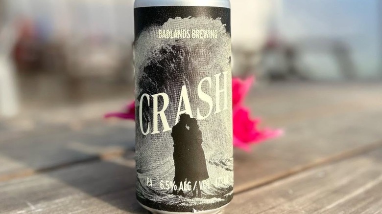 A can of Badlands Brewing Crash beer featuring the image of a couple in silhouette in front of a wave.