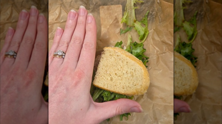 Tiny sandwich on brown paper next to a person's hand