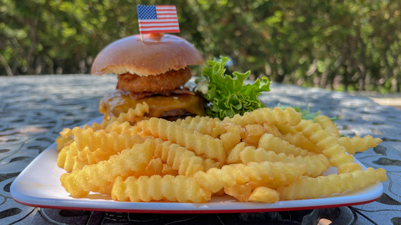 American flag staked into a burger surrounded by fries