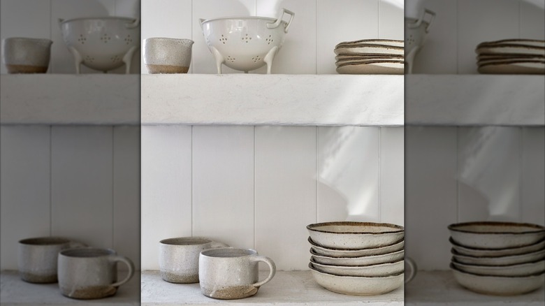 open shelving in a boho coastal style kitchen with white painted v groove wall paneling, mirrored image
