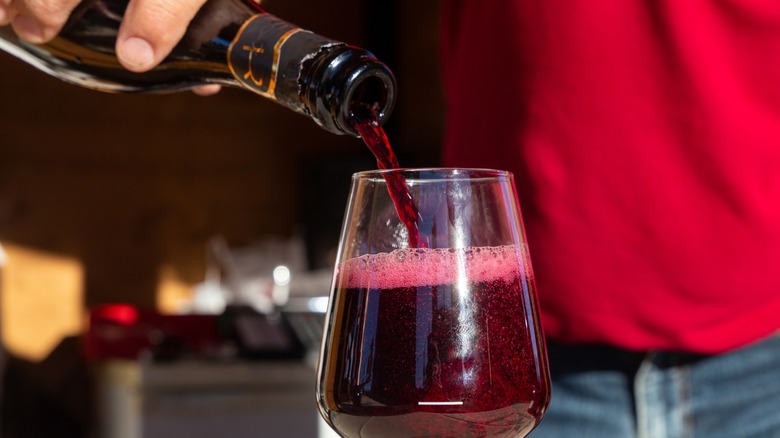a person pouring sparkling red wine into glass