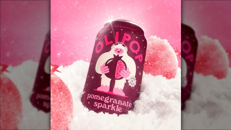 A can of OLIPOP Pomegranate Sparkle soda in a pile of snow with sparkling pomegranates