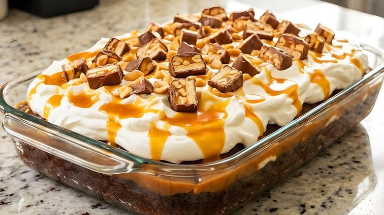 A Snickers poke cake with slices of the candy bar on top.