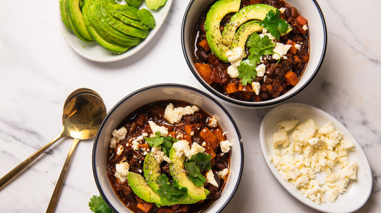 Two garnished bowls of mole turkey and sweet potato chili