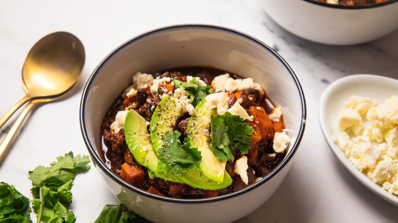 A garnished bowl of mole turkey and sweet potato chili