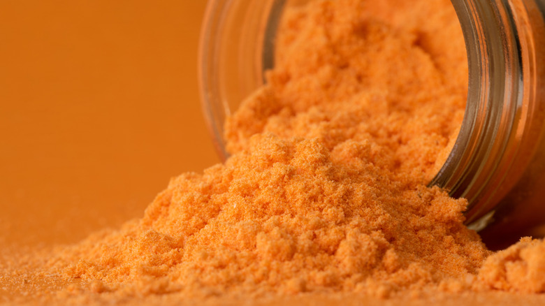 Cheddar cheese powder spilling out of a jar