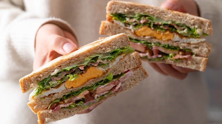 Hand holding two halves of an egg sandwich