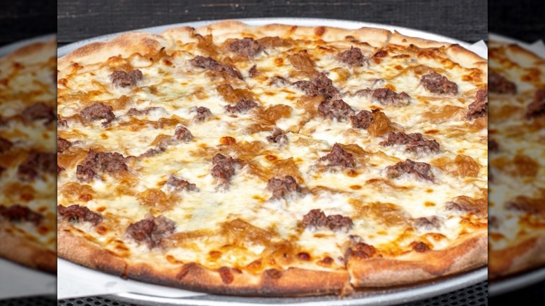 Close-up of thin-crust pizza with meat and cheese on metal pizza tray