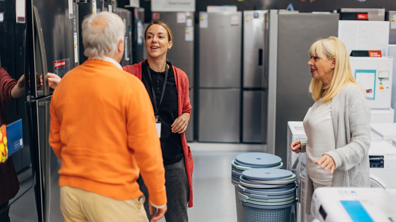 An older couple shopping for a refrigerator with a top freezer at an appliance store
