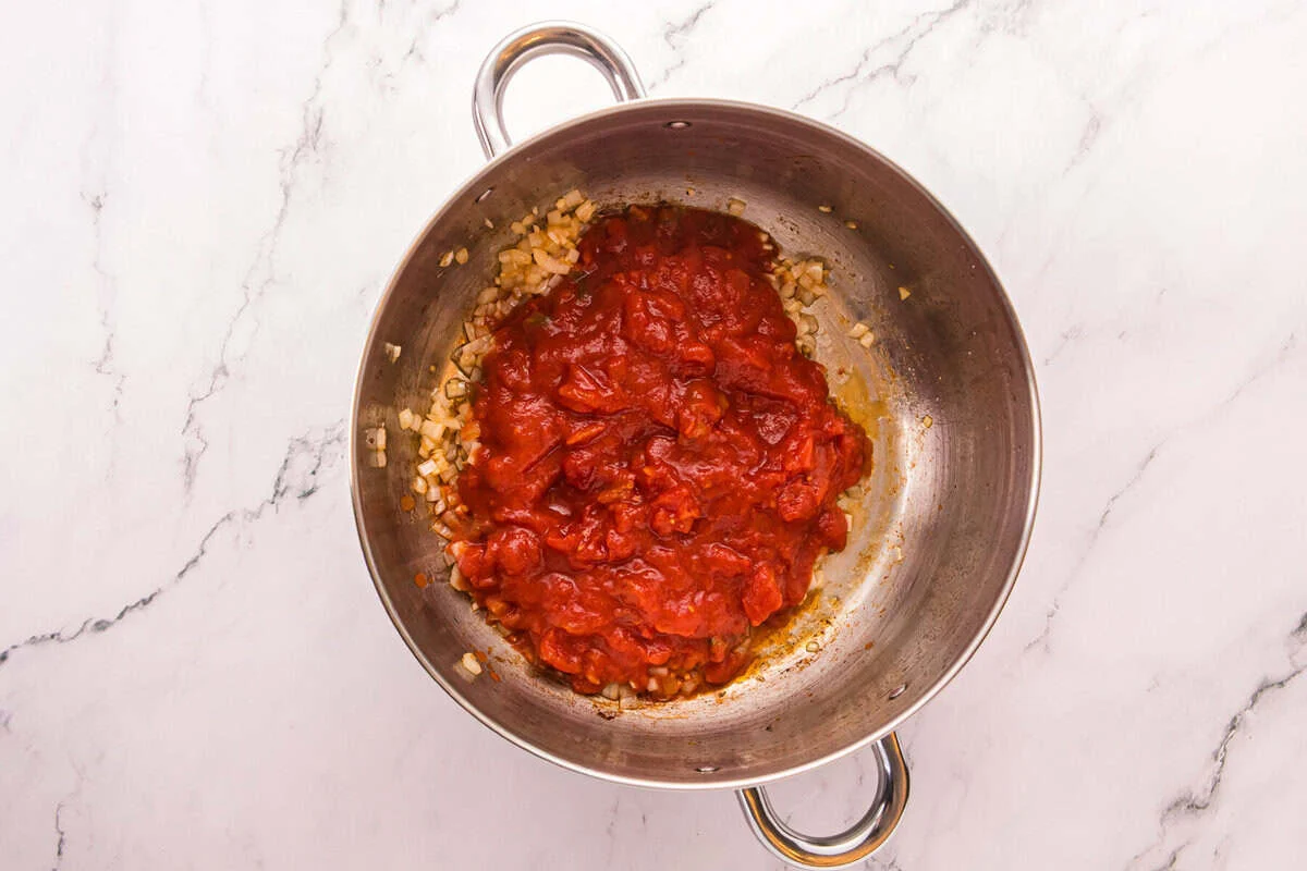 Rotel diced tomatoes with green chiles added to saut&eacute;ed onion and garlic in a pot.