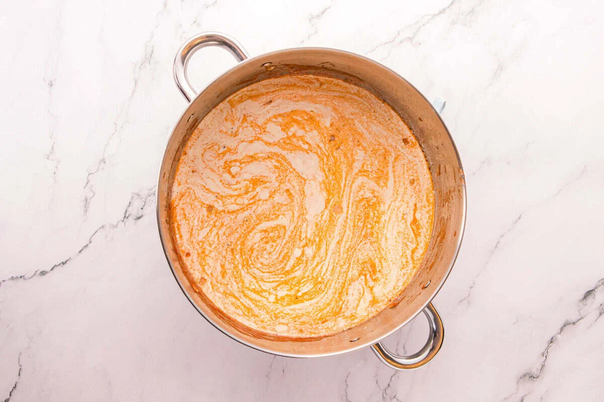 Chicken broth and heavy cream swirled together with Rotel in a stainless steel pot.
