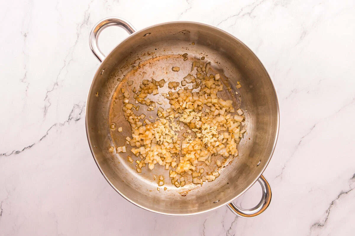 Diced onion and minced garlic saut&eacute;ing in a stainless steel pot.