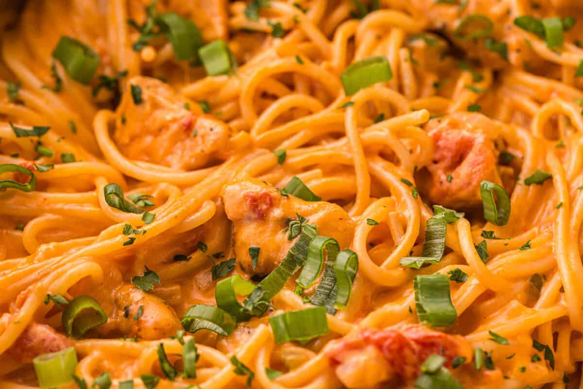 Close-up of creamy one-pot chicken spaghetti with Rotel tomatoes, green onions, and parsley.