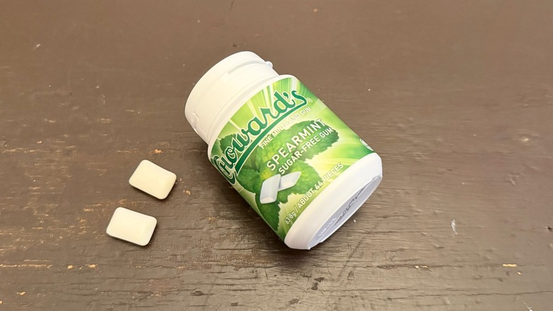 A bottle of Choward's Spearmint Sugar-Free Gum next to two pieces of the gum on a table