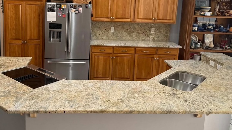 A kitchen with Colonial Cream granite countertops and warm oak cabinetry