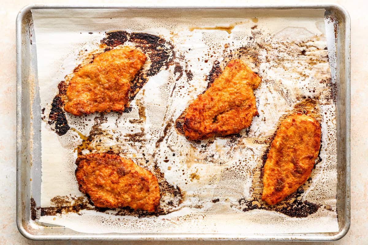 Crispy golden chicken breasts on a parchment-lined baking sheet right out of the oven.