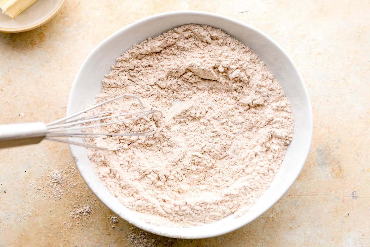 Seasoned flour mixture whisked together in a white bowl for coating the chicken.
