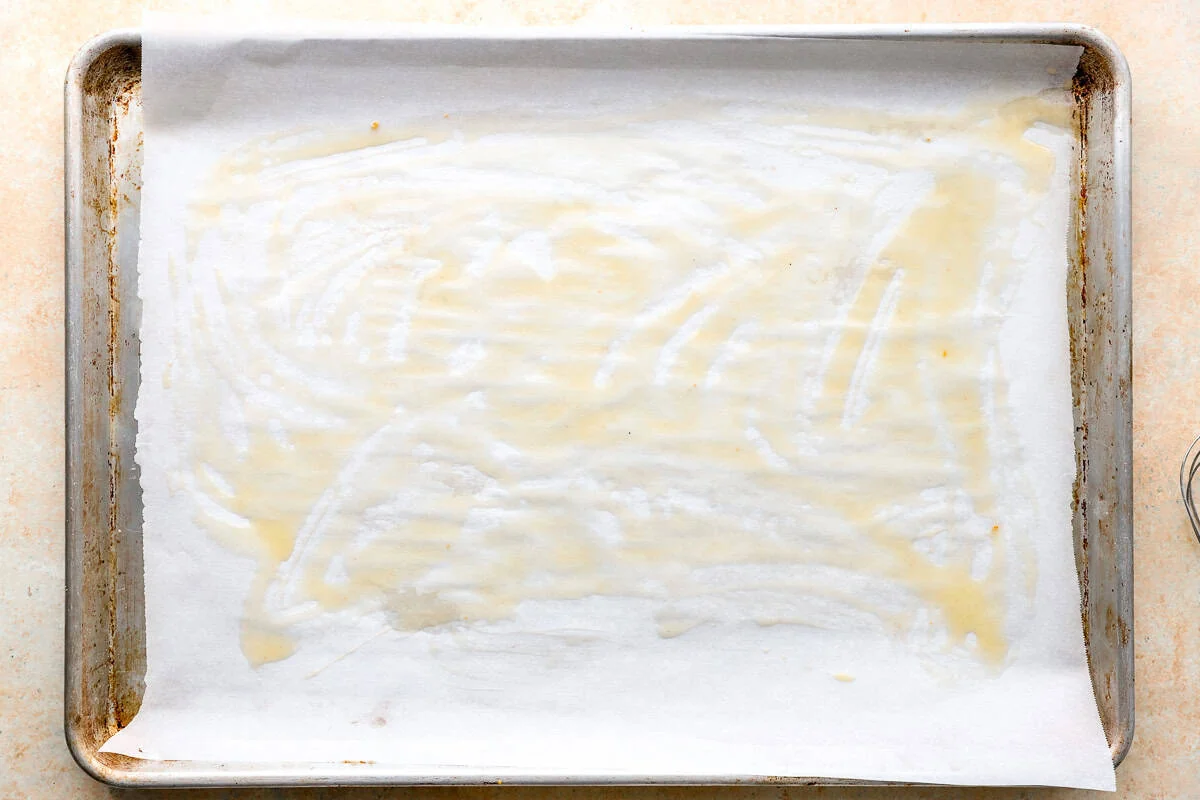Parchment-lined baking sheet brushed with melted butter before adding the chicken.