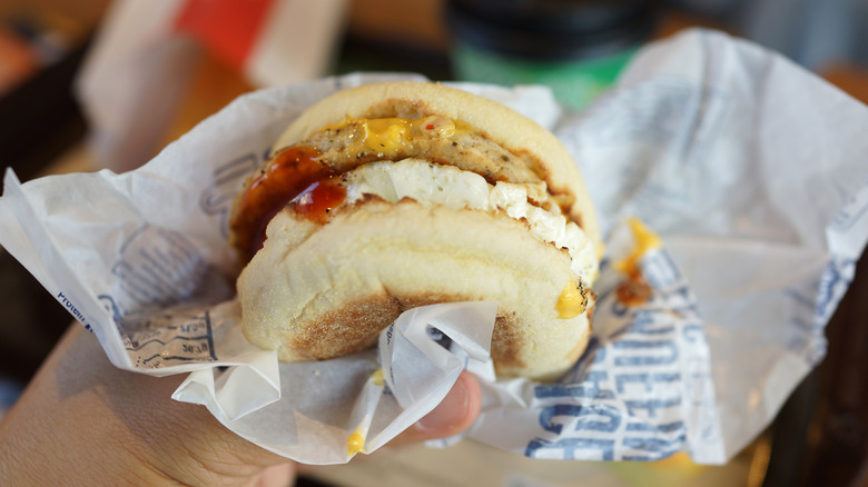customer holding McDonald's Egg McMuffin